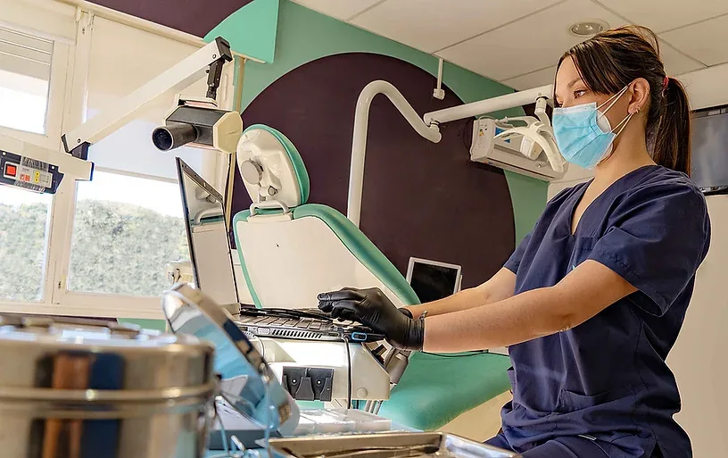 Como automatizar uma clínica odontológica: imagem ilustrativa de um dentista utilizando o computador em seu consultório odontológico.