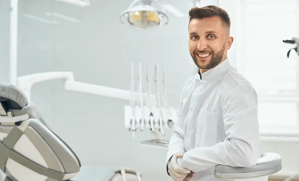 Como atrair pacientes para o consultório odontológico. Dentista vestindo uniforme branco, sentado no consultório odontológico
