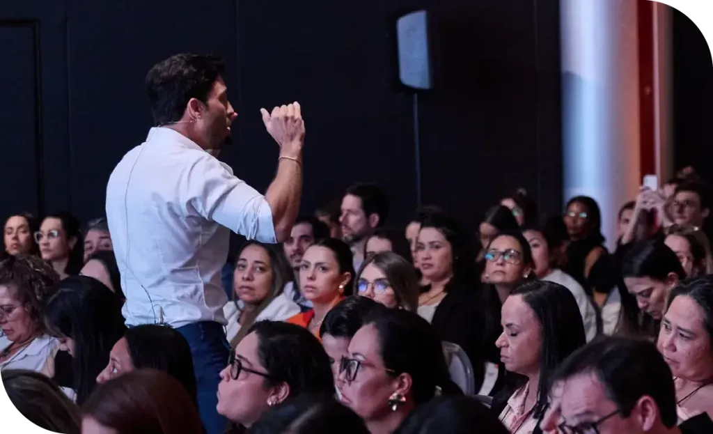 Palestrante diante de uma plateia cheia em evento de odontologia