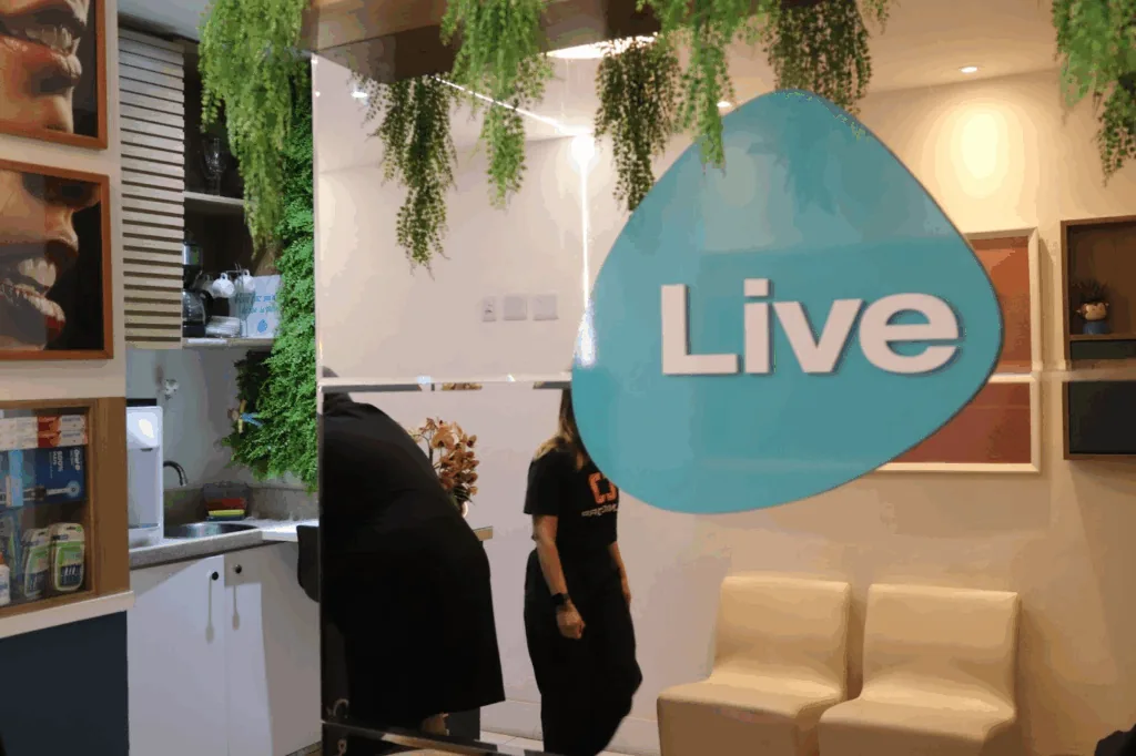 Recepção de clínica odontológica com plantas e o logotipo da clínica na parede